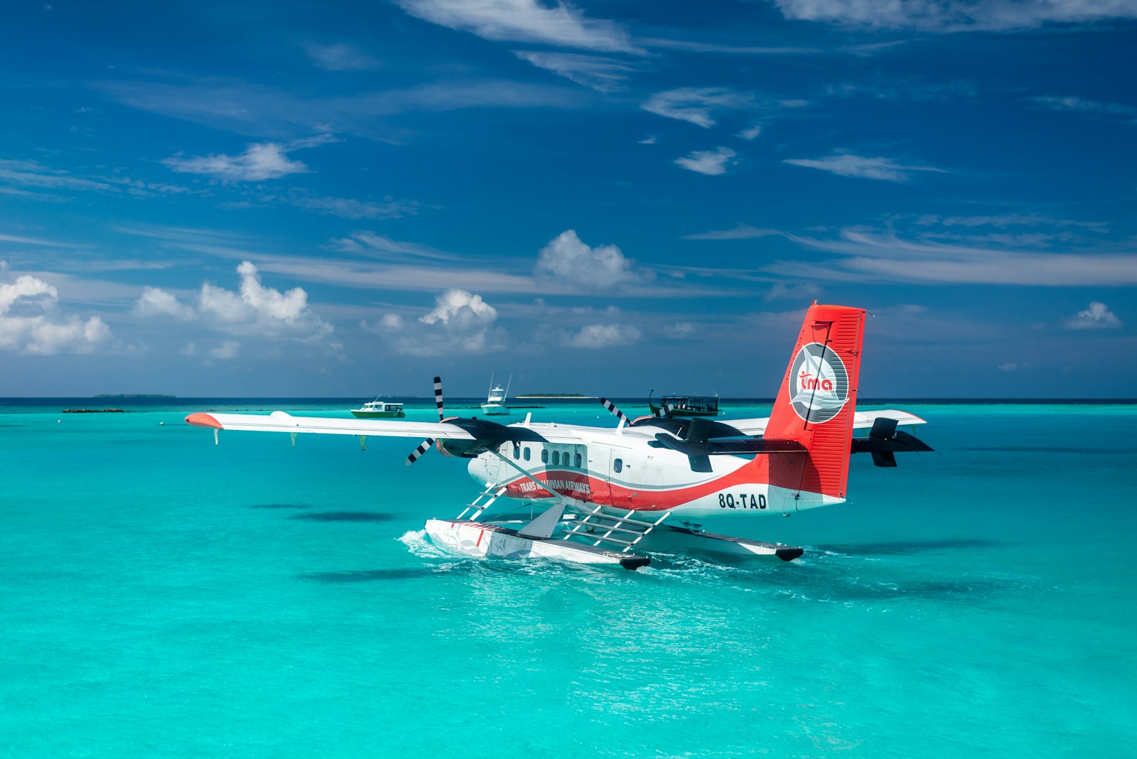 Red and white seaplane resting on bright turquoise water in the Maldives